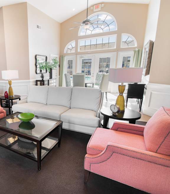 A living room with a pink chair and a white couch.