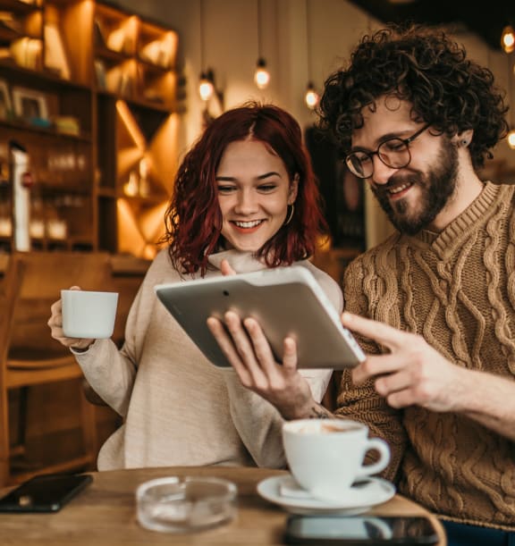 a man and woman sitting at a table looking at a tablet computer