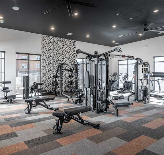 A gym with a variety of equipment including treadmills, weights, and exercise machines.