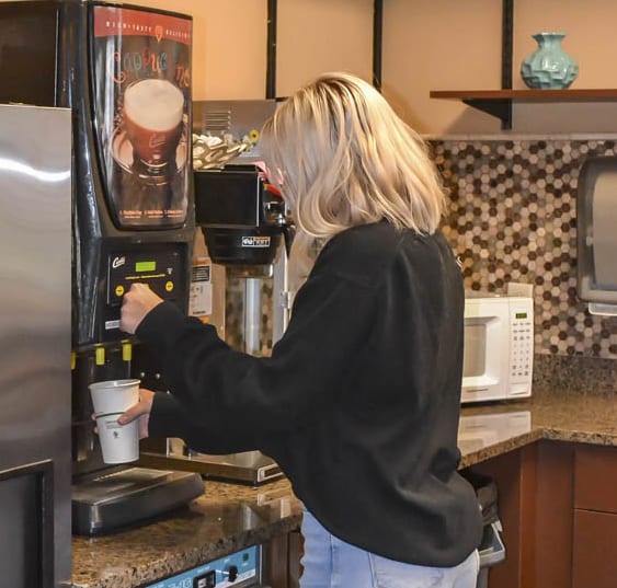 a woman pouring coffee into a coffee maker in a kitchen at Boulder Ridge, Duluth Minnesota