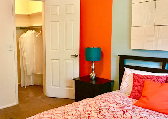 A bedroom with a bed, nightstand, and closet.