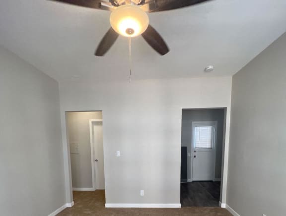 a living room with white walls and a ceiling fan