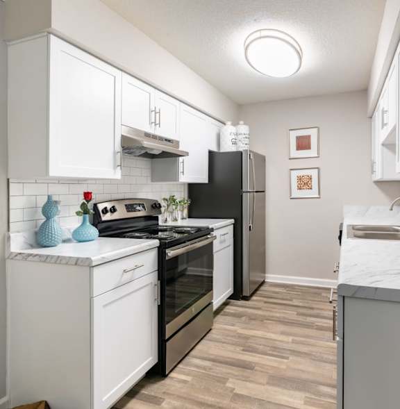 A kitchen with white cabinets and a black refrigerator.