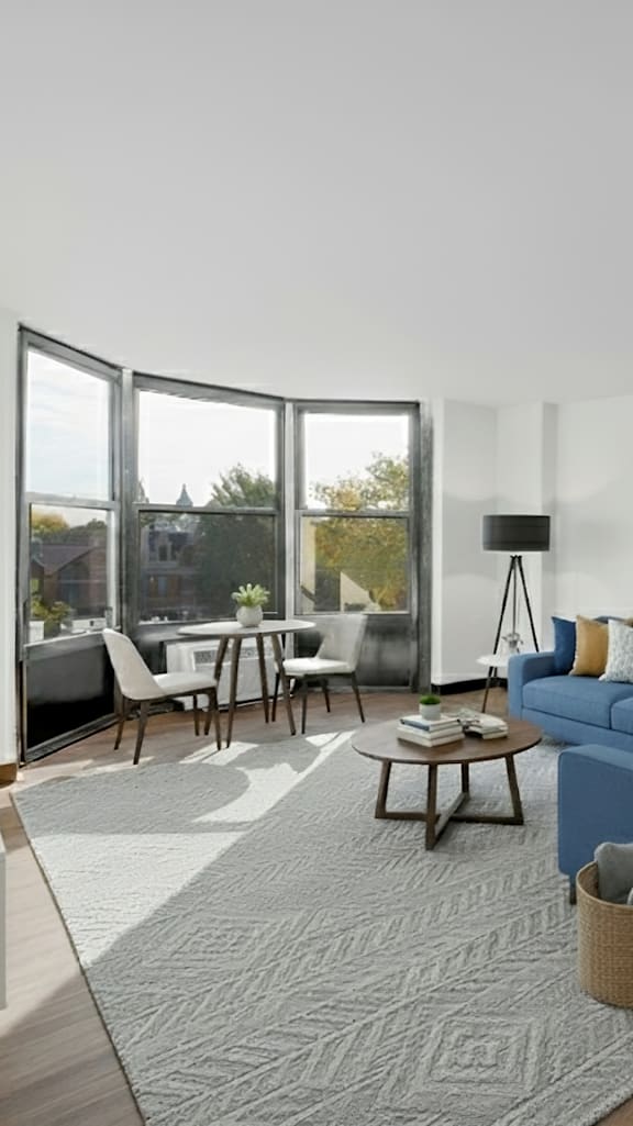 A modern living room with a blue sofa and a grey rug at Fullerton Court Apartments, Chicago