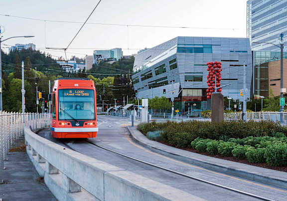 A red light rail bus moving on a track within the city.