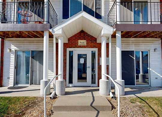 a red brick building with white pillars and a white front door with an awning, and balconies with black metal railings