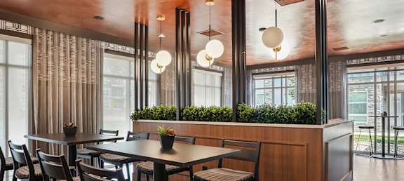 a dining area with tables and chairs and a counter with plants