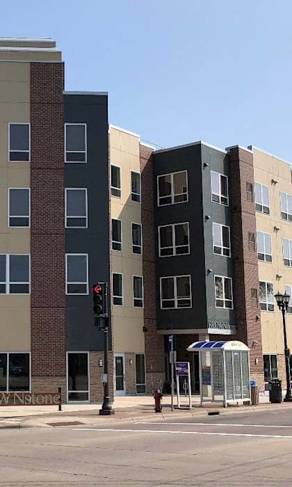 A street view of a multi-story building with a green street sign in front.