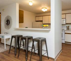 A kitchen with white cabinets and a bar area with stools at Rosemont Place Apartments, Des Moines, IA, 50320