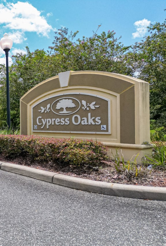 the front of a brick building with a sign and a tree