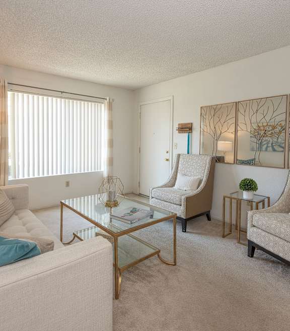 River Pointe model apartment living room with chairs, coffee table, couch, and wall art
