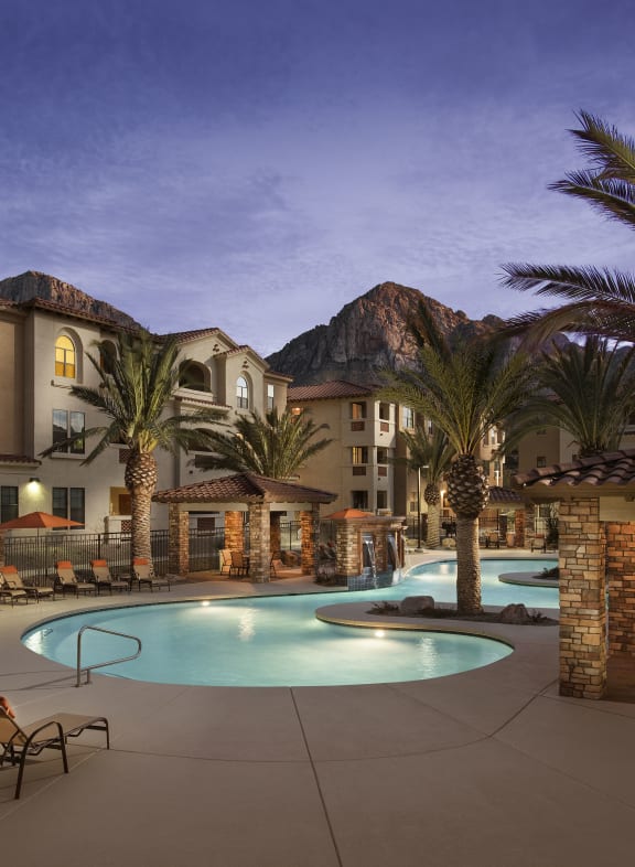 a swimming pool with chaise lounge chairs and palm trees in front of an apartment complex at Villas at San Dorado, Oro Valley, Arizona
