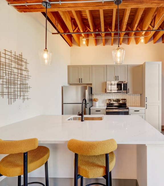 a kitchen with a white counter top and a large window at Greeley Lofts, St. Louis, MO, 63102