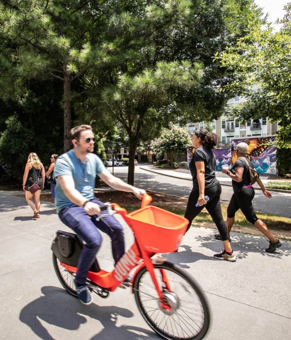 Man riding bike on The Atlanta Beltline, adults in background excersing and walking on beltine in Atlanta, GA