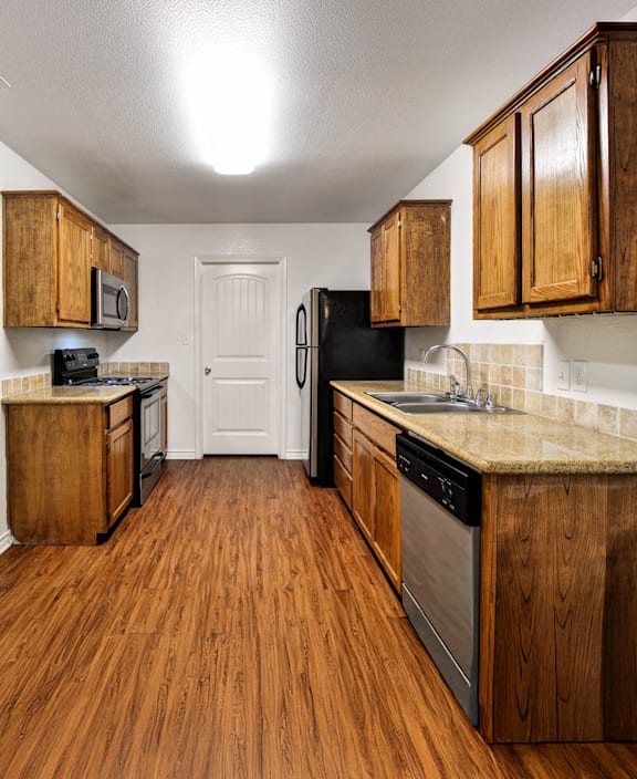 A kitchen with wooden cabinets and a black refrigerator.