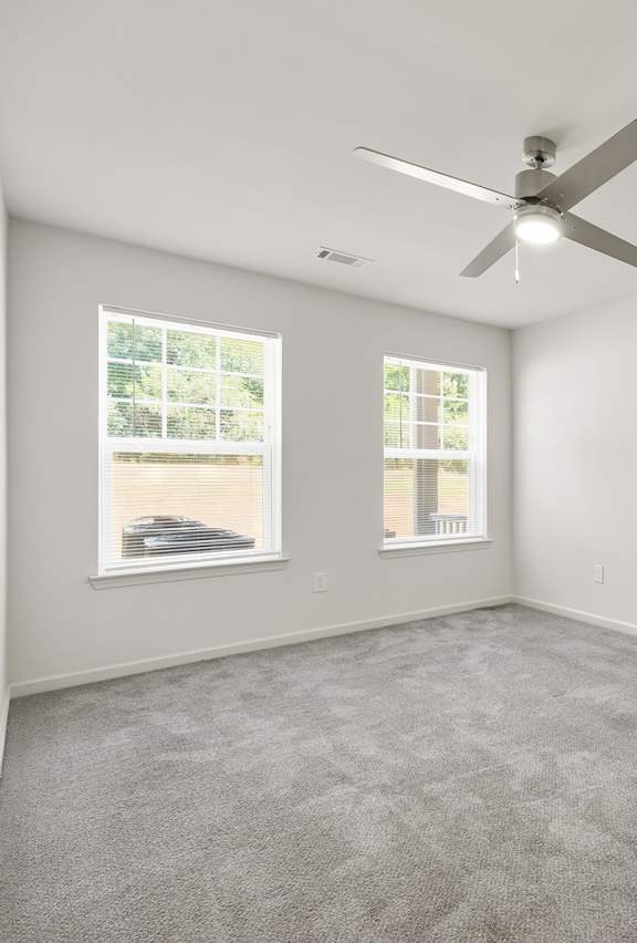A room with a ceiling fan and car pictures on the wall.