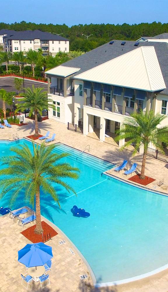 a large swimming pool with palm trees in front of a large apartment complex at Alaqua, Florida, 32258 at Alaqua Apartments, Florida, 32258