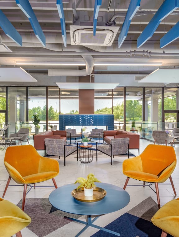 a large lobby with yellow chairs and tables and windows