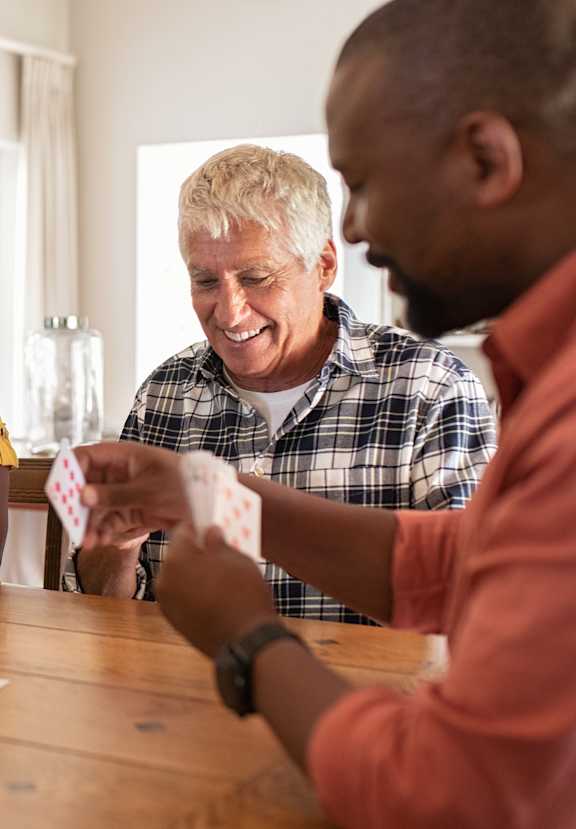 A group of people playing a card game at a table.