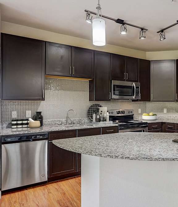 A kitchen with a granite countertop and stainless steel appliances.