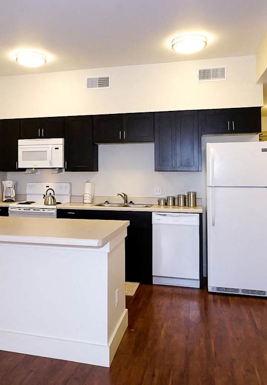 Kitchen with white appliances and dark cabinets