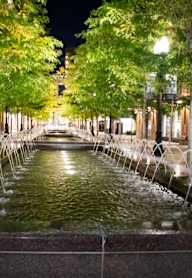 A fountain in the middle of a city street at night.