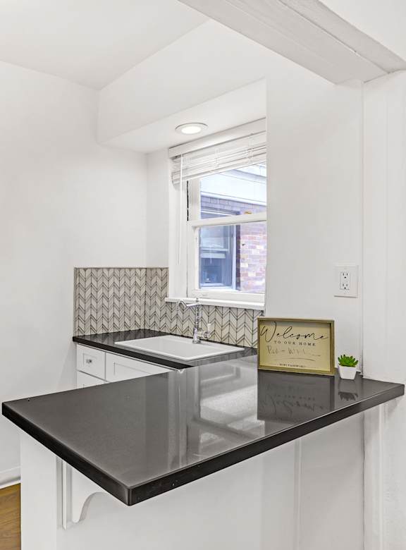 A kitchen with a black counter top and a stainless steel refrigerator.at Park Wilshire, Los Angeles, CA 90057