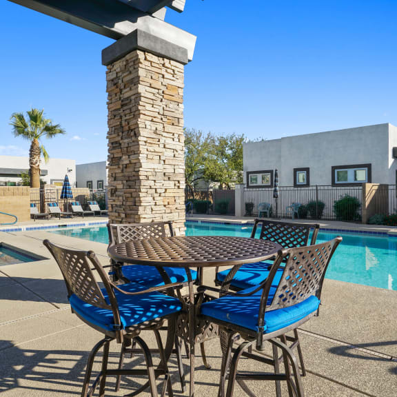 a patio with a table and chairs next to a swimming pool