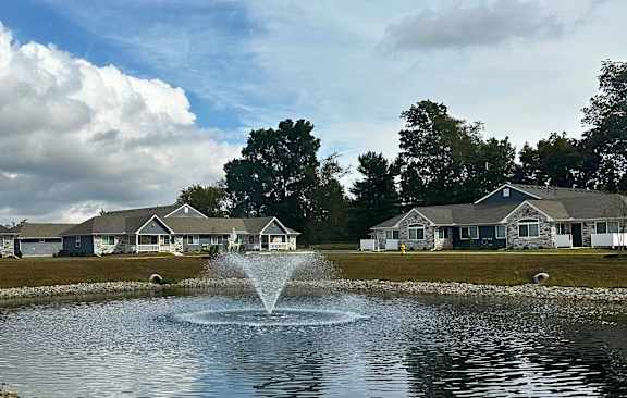 a fountain in the middle of a pond with houses in the background