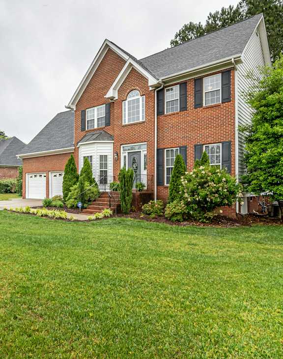 A large house with a red brick exterior and a white trim.