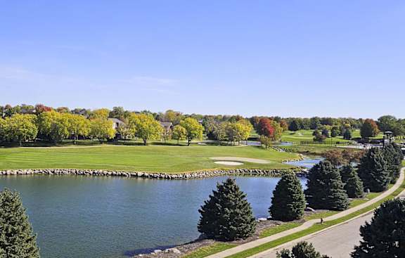 a view of a golf course and a pond surrounded by trees