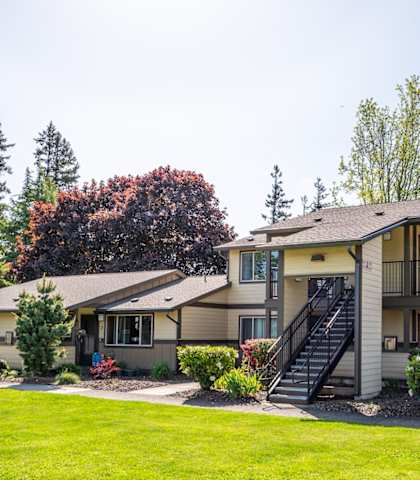 the view of a building with a green lawn and trees