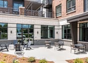 Thumbnail 24 of 28 - A patio with chairs and tables is surrounded by a brick building.