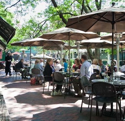 a group of people sitting at tables under umbrellas