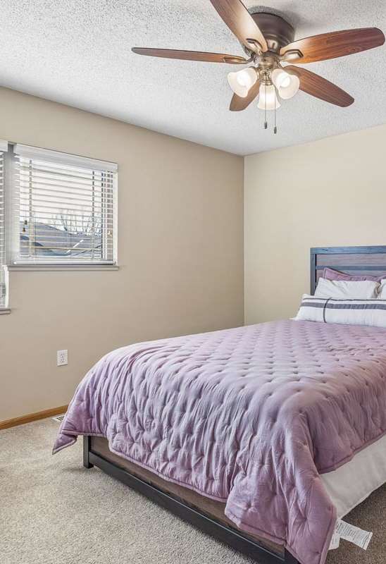 A bedroom with a bed, nightstand, and a ceiling fan.