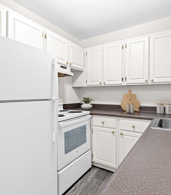 A white refrigerator is in a kitchen with white cabinets.