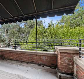 A balcony with a black railing and a wooden fence.