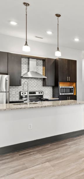 an empty living room with a kitchen with a counter top and