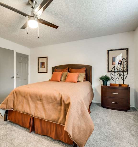 A bedroom with a bed, nightstand, and a ceiling fan.