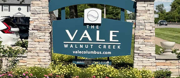 A sign for Vale Watercolor in front of a parking lot.
