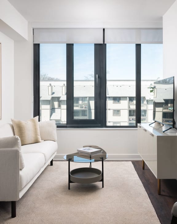 a living room with white furniture and a large window