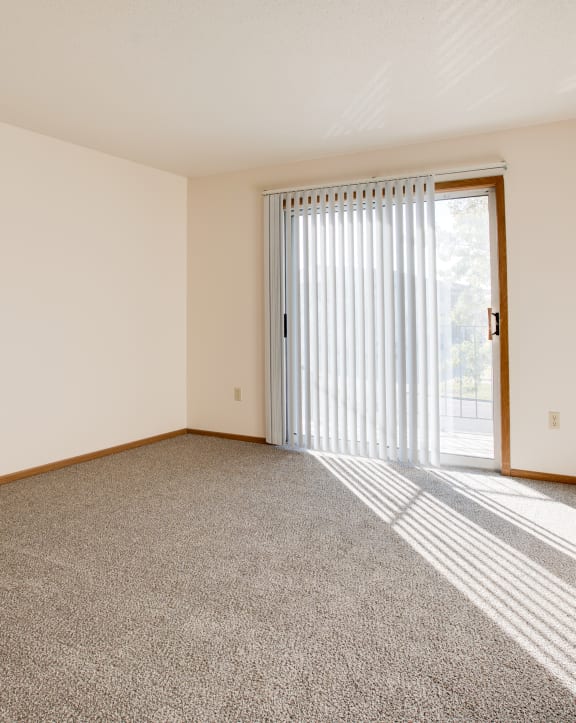 an empty living room with a kitchen in the background