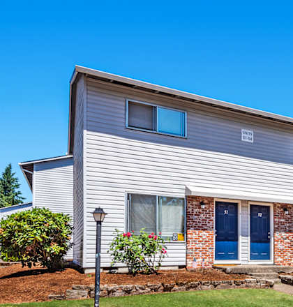 a white house with blue shutters and a red curb