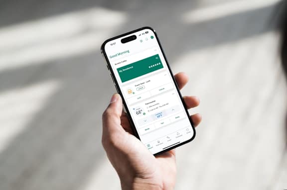 A person is holding a smartphone displaying the SmartRent app