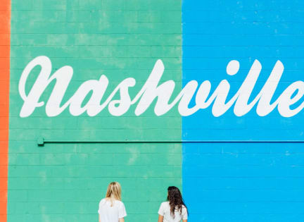 two women walking in front of a blue wall written on it