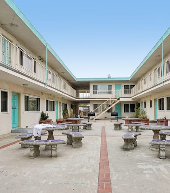 A pool with a hot tub and lounge chairs in front of a building.
