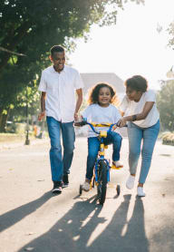 A family of three is walking together in a park with a child on a bicycle. at Brookstone, Washington, 98198