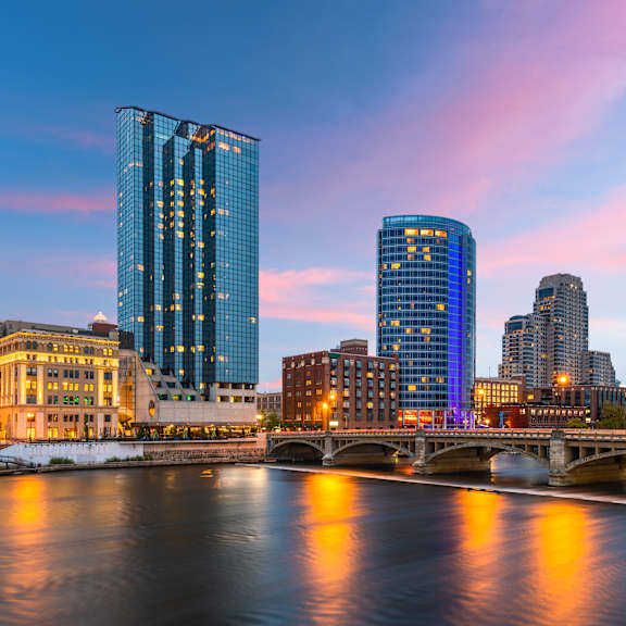 A cityscape with a river in the foreground and buildings reflecting on the water.