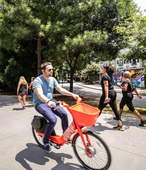 Man riding bike on The Atlanta Beltline, adults in background excersing and walking on beltine in Atlanta, GA