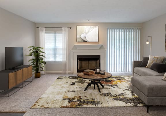 A living room with a grey couch, a white chair, a black table, and a television.